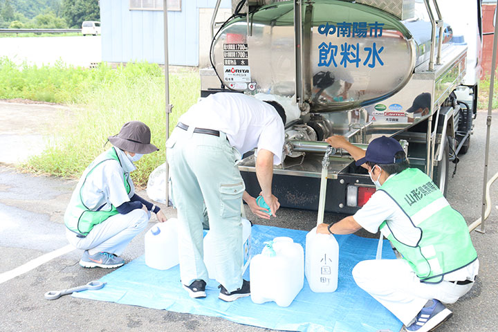 南陽市の給水車から水を汲む職員の写真